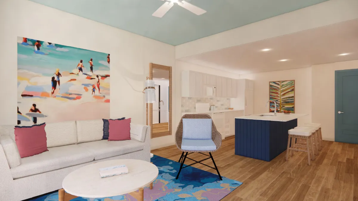 The image showcases a bright, contemporary living area with a stylish sofa, vibrant artwork on the wall, and a spacious kitchen island, inviting guests to relax, socialize, or cook together in a welcoming environment.